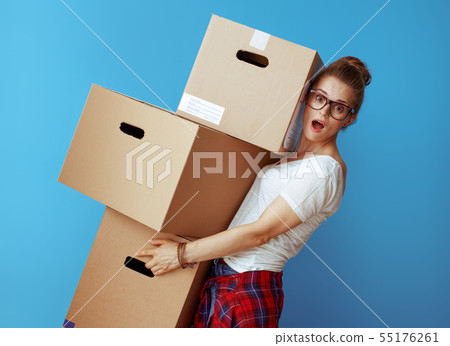 shocked modern woman holding pile of cardboard boxes on blue shocked modern woman holding pile of cardboard boxes on blue 55176261