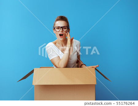 young woman in cardboard box telling exciting news on blue young woman in cardboard box telling exciting news on blue 55176264