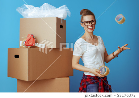 woman near cardboard box throwing up adhesive tapes on blue woman near cardboard box throwing up adhesive tapes on blue 55176372