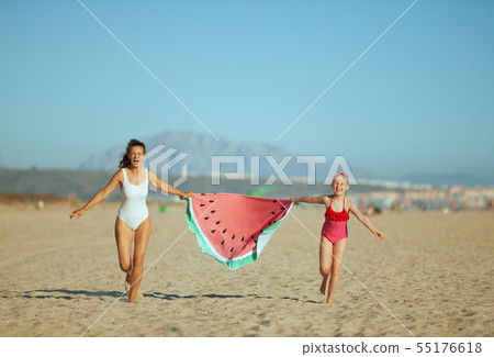 mother and daughter holding funny watermelon towel and running mother and daughter holding funny watermelon towel and running 55176618