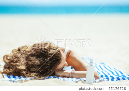 healthy woman with suntan lotion laying on striped towel healthy woman with suntan lotion laying on striped towel 55176728