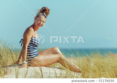 happy young woman in striped swimsuit sitting on seashore happy young woman in striped swimsuit sitting on seashore 55176830