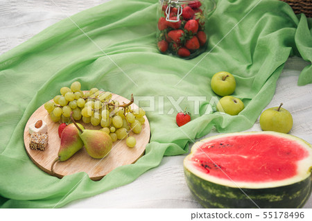 Summer picnic in the meadow on the green grass. Fruit basket, juice and bottled wine, watermelon 55178496