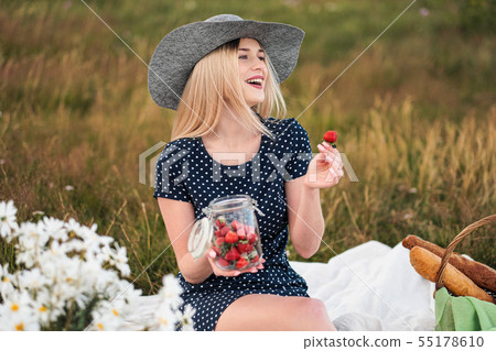 Young attractive woman in a blue dress at an outdoor picnic. A basket with daisies, watermelon Young attractive woman in a blue dress at an outdoor picnic. A basket with daisies, watermelon 55178610