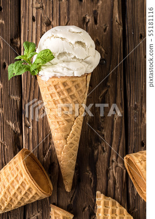 Top view white ice cream in waffle cone on rustic background 55181116