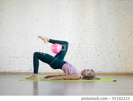 Gluteal bridge with pink small fit ball. Caucasian girl doing pilates with special equipment in 55182223