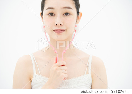 A woman using a small face massage device 55182653