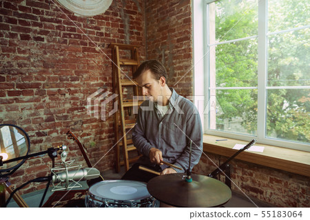 Young man recording music, playing drums and singing at home Young man recording music, playing drums and singing at home 55183064