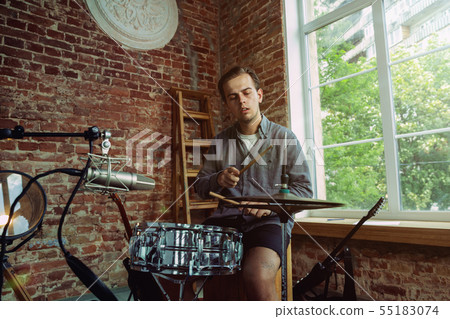 Young man recording music, playing drums and singing at home Young man recording music, playing drums and singing at home 55183074