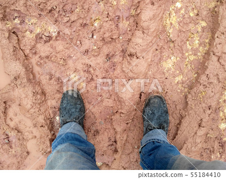 A man wearing steel toe shoes and standing in mud. A man wearing steel toe shoes and standing in mud. 55184410