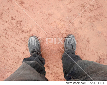 A man wearing steel toe shoes and standing in mud. A man wearing steel toe shoes and standing in mud. 55184411