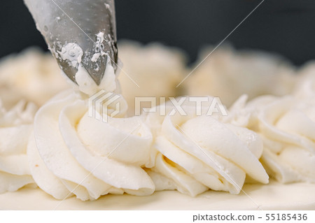 Decorating a white cake with cream from the pastry bag. Macro shot, closeup. Decorating a white cake with cream from the pastry bag. Macro shot, closeup. 55185436