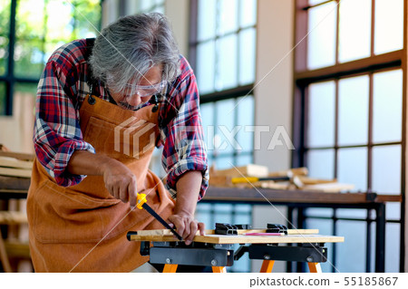 Old Asian craftsman is working with saw to cut 55185867
