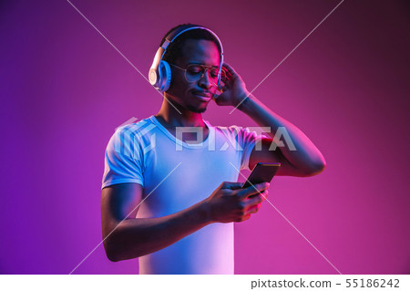 Young african-american man's listening to music in neon light Young african-american man's listening to music in neon light 55186242