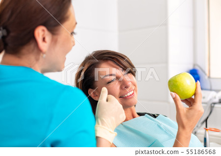 A happy patient at the reception at the stamatologist, checks the health of the teeth, bites green A happy patient at the reception at the stamatologist, checks the health of the teeth, bites green 55186568