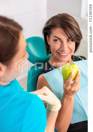 A happy patient at the reception at the stamatologist, checks the health of the teeth, bites green A happy patient at the reception at the stamatologist, checks the health of the teeth, bites green 55186569