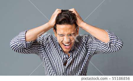 Frustrated Young Man Pulling His Hair Out On Gray Background 55186856