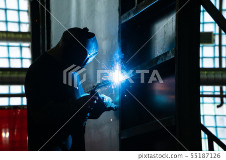 Welder in his workshop welding metal, lots of sparks flying around Welder in his workshop welding metal, lots of sparks flying around 55187126