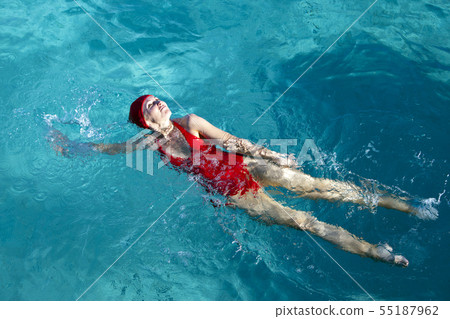young woman in a red bathing suit swimming in the  55187962