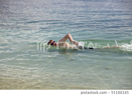 young man in sport glasses swims in the sea 55188185