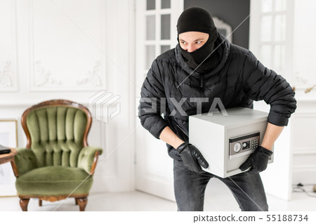 The burglar commits a crime in Luxury apartment with stucco. Thief with black balaclava stealing 55188734