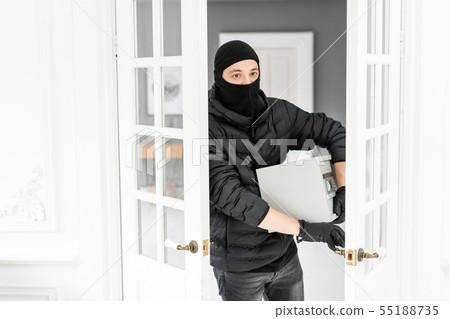 The burglar commits a crime in Luxury apartment with stucco. Thief with black balaclava stealing 55188735