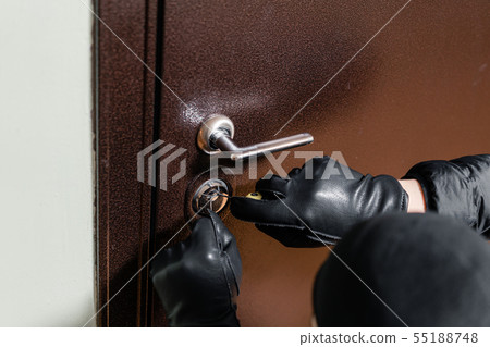 close up of a burglar with gloves picking a lock. Thief with a passkey. 55188748