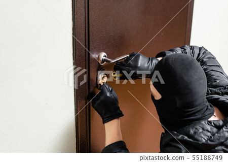 Burglar entering front door of the apartment after successfully picking the lock. 55188749