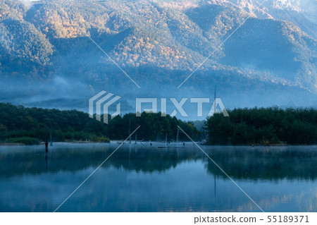 Hotaka mountain range and morning haze Taisho pond stained in autumn leaves 55189371