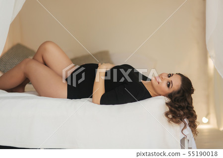 Beautiful pregnant woman lies on the bed in her room. Young lady with long hair put her hands on Beautiful pregnant woman lies on the bed in her room. Young lady with long hair put her hands on 55190018