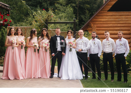 Groom and bride stand with groomsman and bridesmaid outside. Newlyweds kissing and friend clap Groom and bride stand with groomsman and bridesmaid outside. Newlyweds kissing and friend clap 55190817