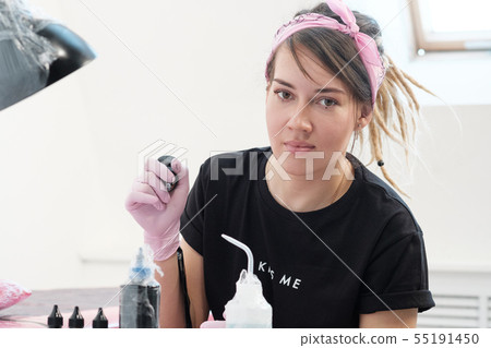 Portrait of a professional tattoo master woman. Black clothes, and dreadlocks. Red, pink and white 55191450