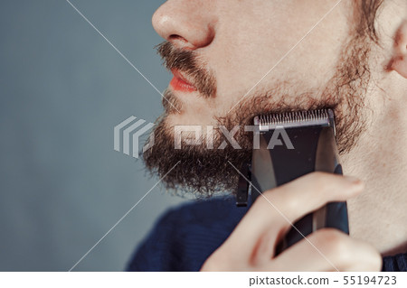 guy shaves his beard with an electric razor 55194723
