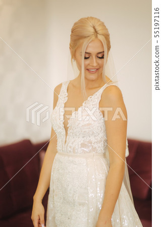Elegant bride in beautiful wedding dress with bouquet at home. Blond hair woman with beautiful 55197116