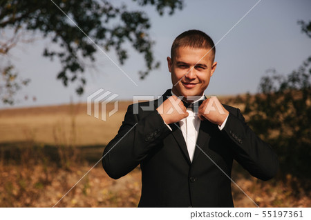 Handsome groomm dressed a tie bow. Wedding day. Man outside. Young man smile Handsome groomm dressed a tie bow. Wedding day. Man outside. Young man smile 55197361