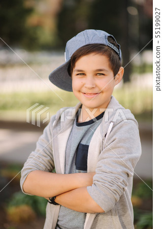Stylish little school boy in blue cap posing outside for photo. Boy walking in the city in sping 55199027