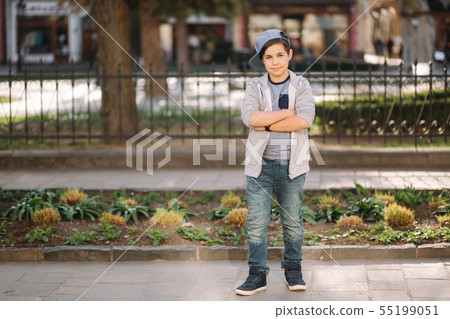 Stylish little school boy in blue cap posing outside for photo. Boy walking in the city in sping 55199051