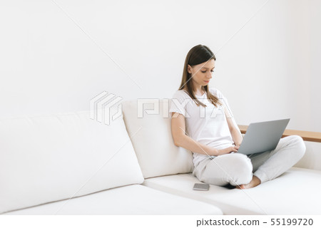 Serious young woman freelancer sitting on soft sofa, freelance from home Serious young woman freelancer sitting on soft sofa, freelance from home 55199720