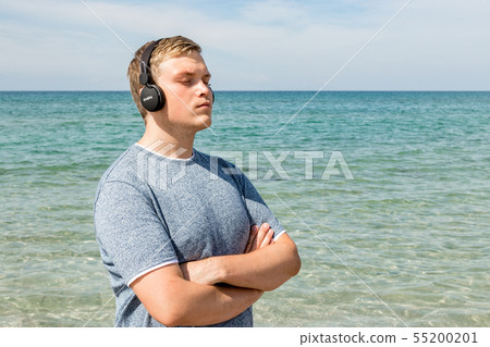 Portrait of a young man on the beach listening to Portrait of a young man on the beach listening to 55200201