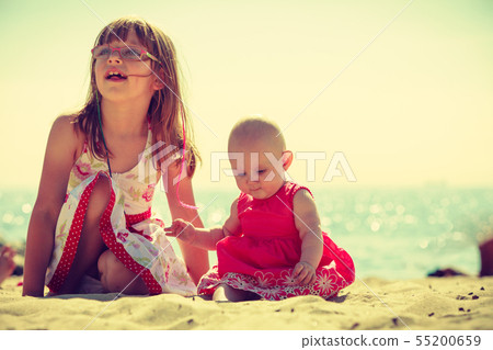 Toddler girl having fun with child on beach. 55200659
