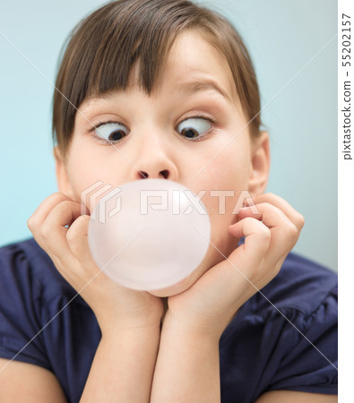Little girl is blowing big bubble gum Little girl is blowing big bubble gum 55202157