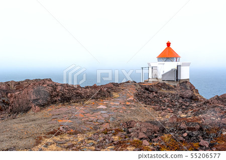 The sea beacon with a red top and a stone footpath 55206577