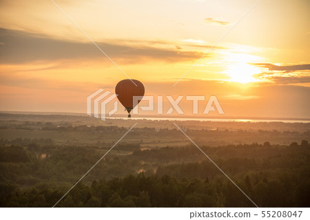 An air balloon flying over the forest on a background of bright sunset 55208047