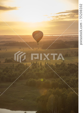 An air balloon flying over the field and trees using heat technology - bright sunset An air balloon flying over the field and trees using heat technology - bright sunset 55208102