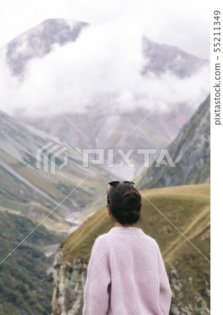 young girl in a sweater is looking at the Caucasian mountains young girl in a sweater is looking at the Caucasian mountains 55211349