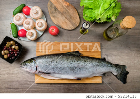 Top view keta fish, whole on the cutting board of the kitchen table next to olives tomatoes and Top view keta fish, whole on the cutting board of the kitchen table next to olives tomatoes and 55214113