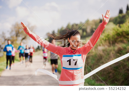 Young woman runner crossing finish line in a race competition in nature. Young woman runner crossing finish line in a race competition in nature. 55214232
