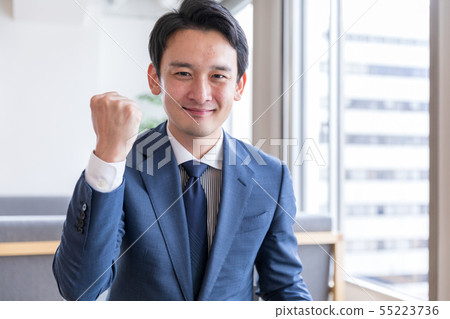 A man in a suit showing a guts pose 55223736