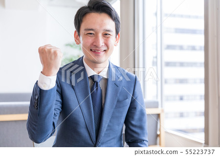 A man in a suit showing a guts pose 55223737