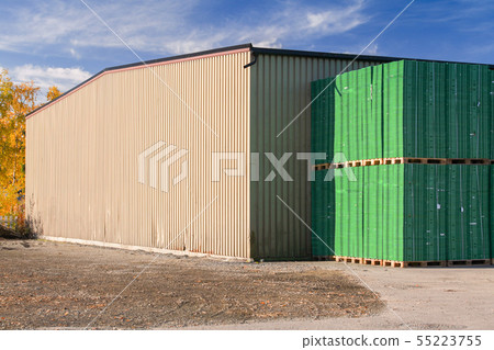 Storage building and stacks of green pallets 55223755